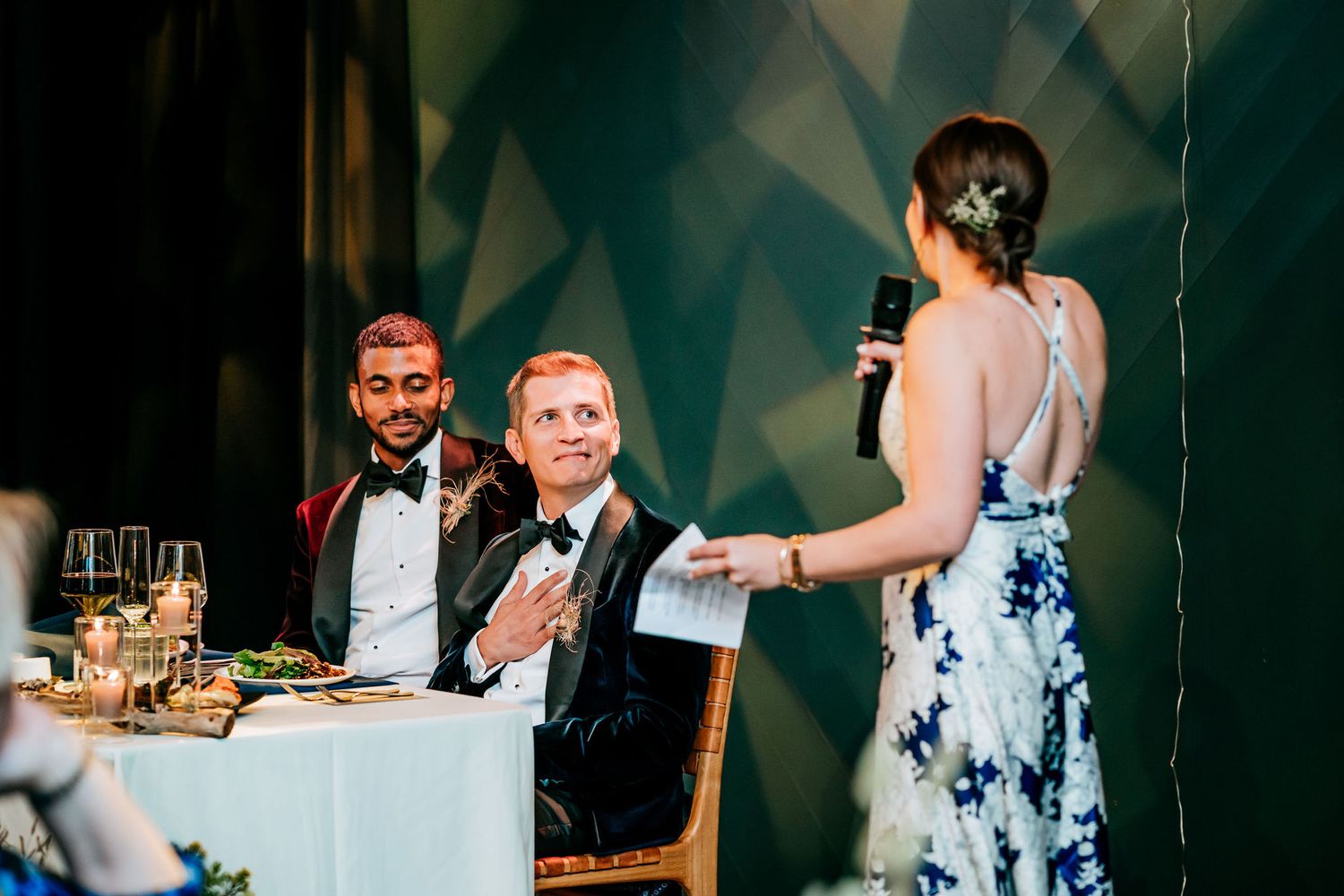 A joyful toast moment during an elegant wedding reception with formal attire and table settings.