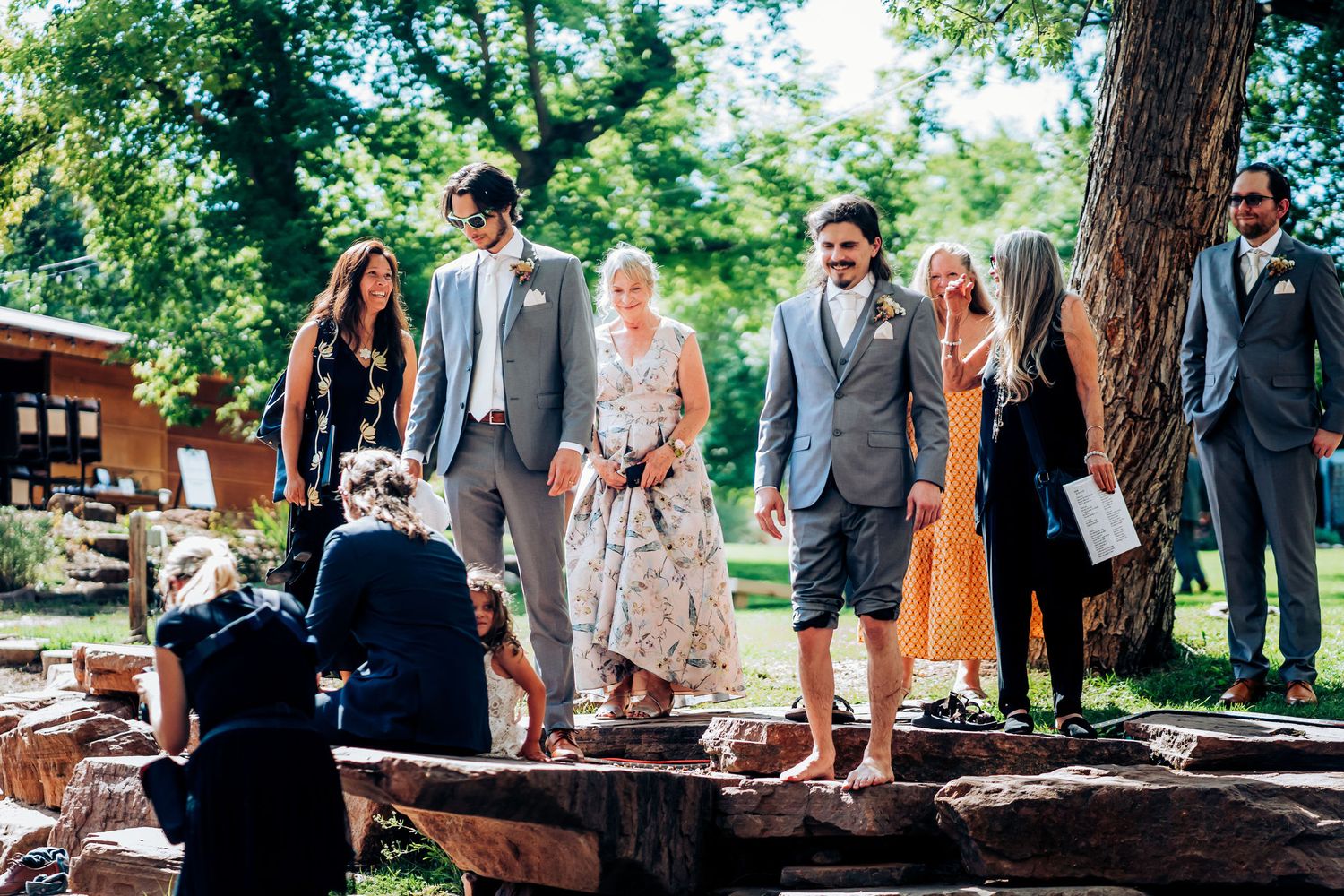 Wedding party gathers on natural stone steps during outdoor ceremony.