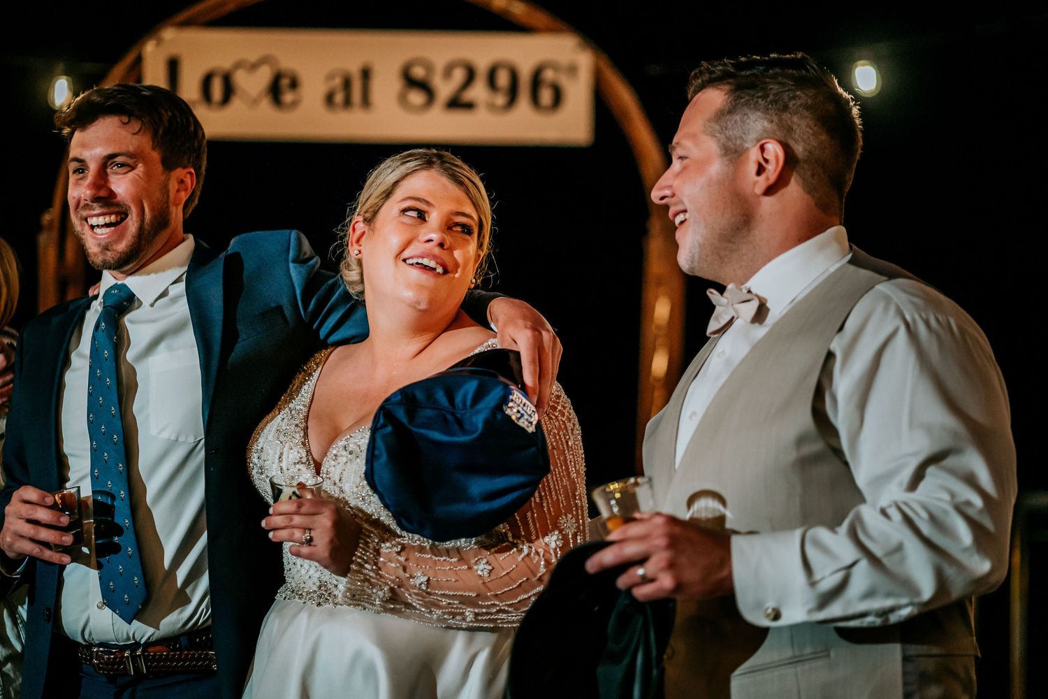 Wedding reception moment captured at night with illuminated signage in background.