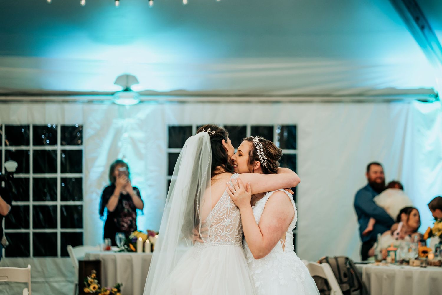 Two people in white wedding dresses sharing an intimate moment during their first dance.
