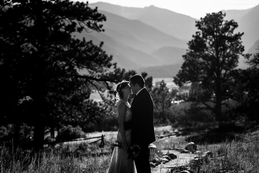Black and white portrait of couple embracing with misty mountains in background.