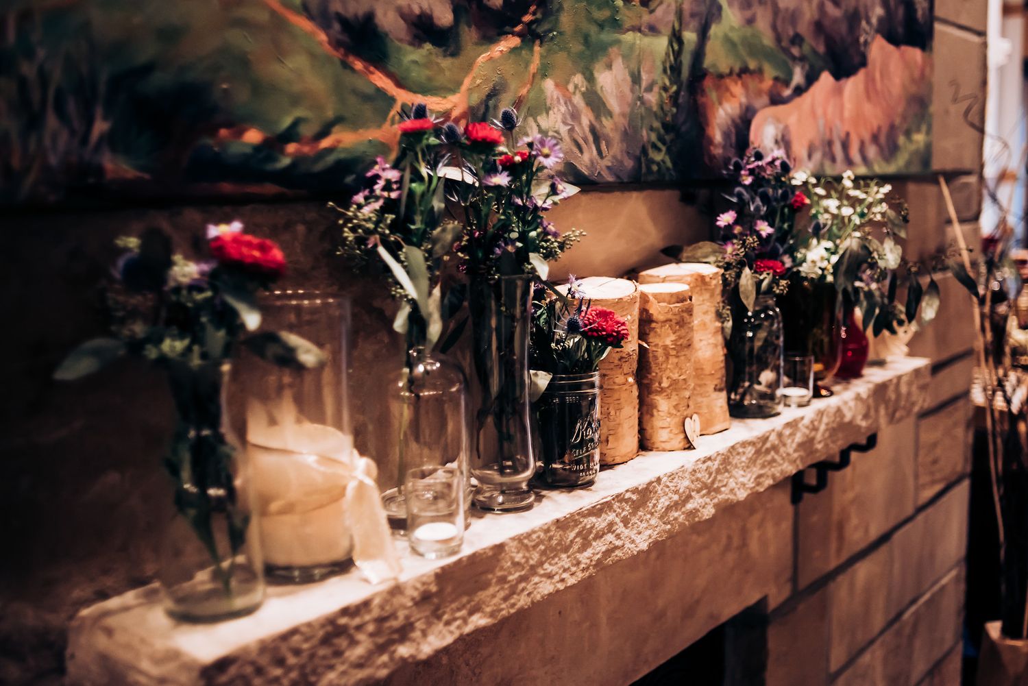 Rustic wedding decor featuring floral arrangements and candles on a wooden shelf.