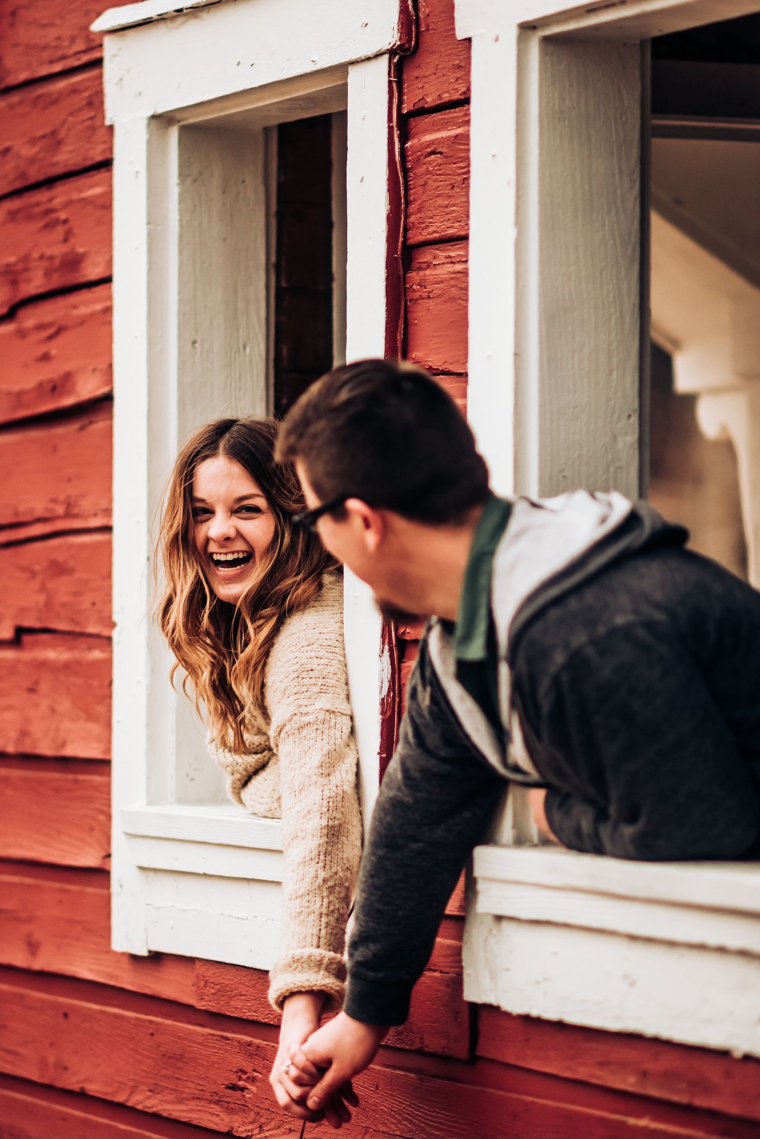 A joyful moment shared between two people at windows of a red building.