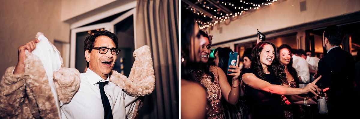 Party guests dance enthusiastically together under decorative string lights.
