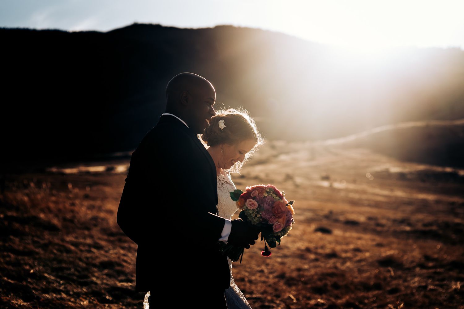 Romantic sunset portrait of newlyweds with mountain backdrop.
