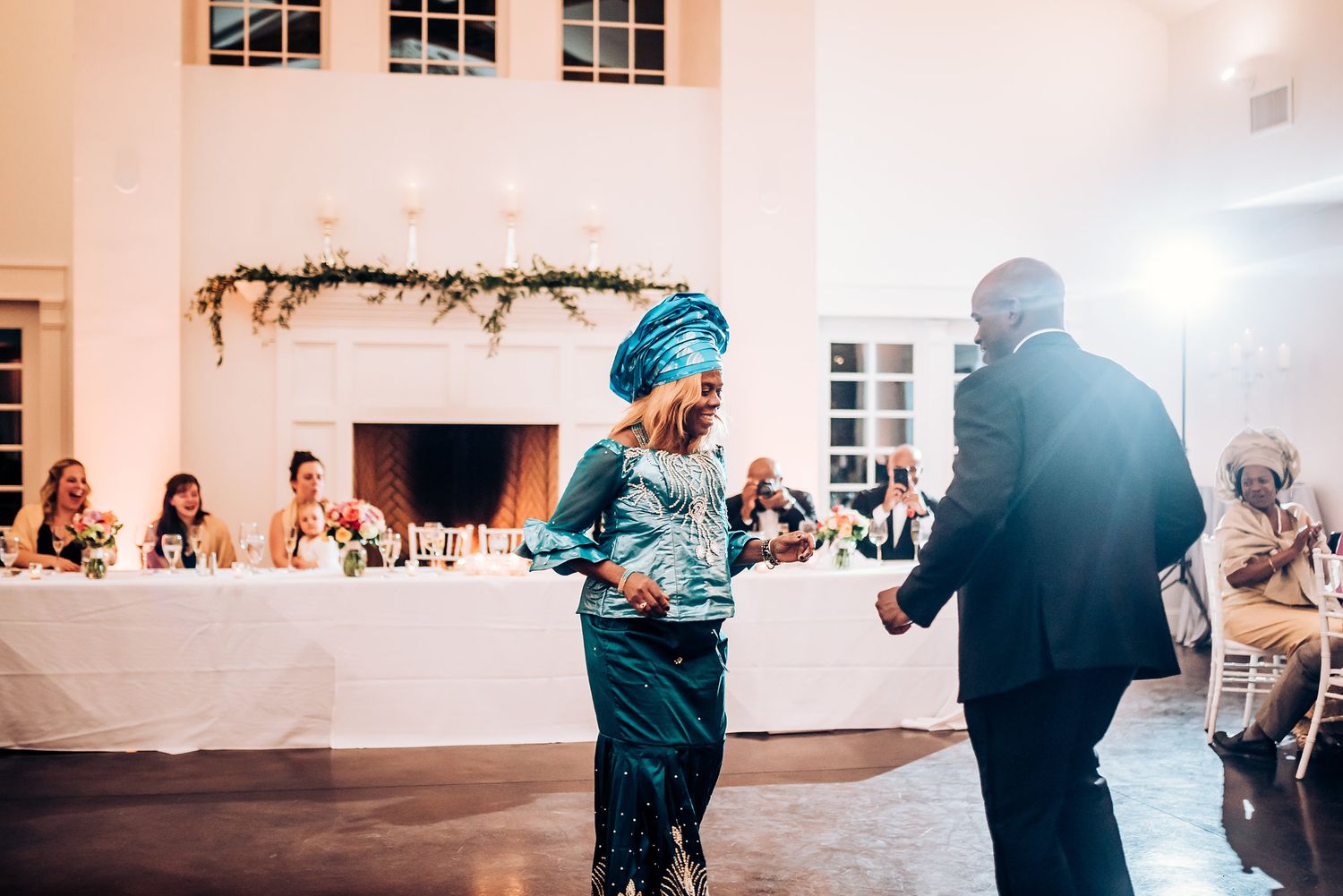 Wedding guests in colorful attire dance during lively reception celebration.