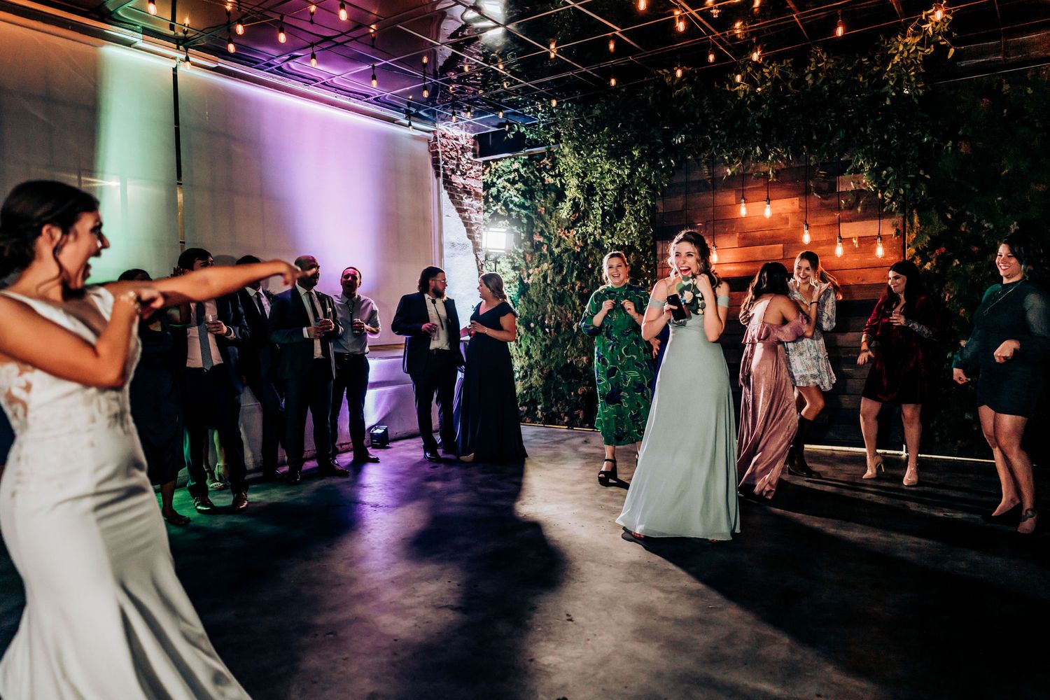 Wedding reception party scene with ambient lighting and decorative greenery.