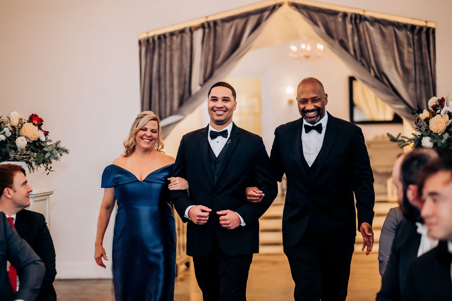 Wedding party members walk arm in arm during a formal ceremony entrance.