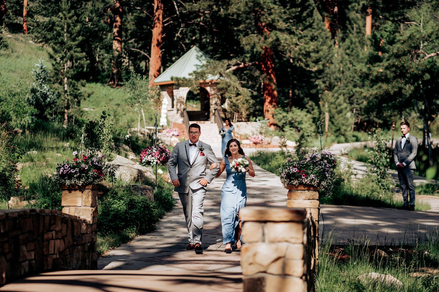 Celebration on a scenic mountain pathway with stone walls and pine trees.