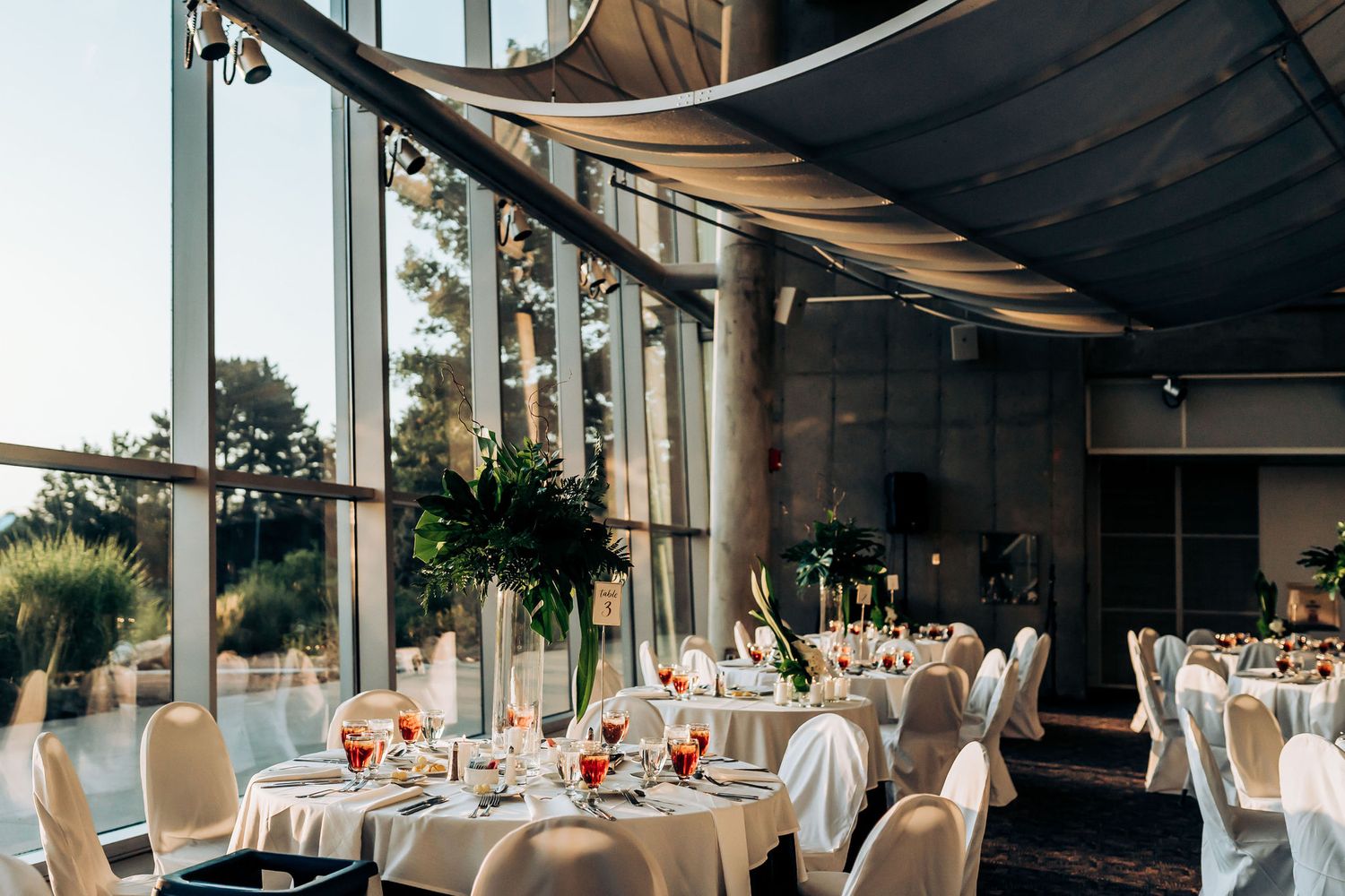 A modern wedding reception venue with curved architecture and round tables set for dinner.