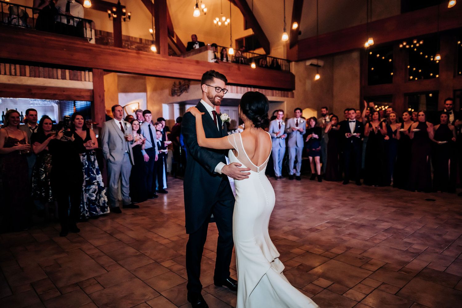 A romantic slow dance moment captured at an evening wedding reception with ambient lighting.