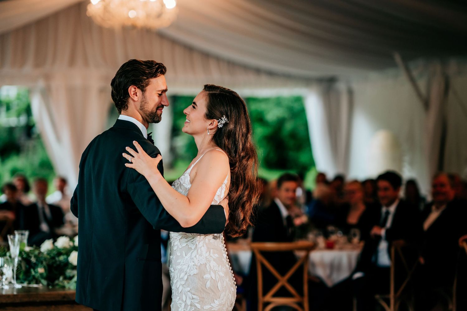 Couple sharing their first dance in an elegant tent reception with romantic lighting.