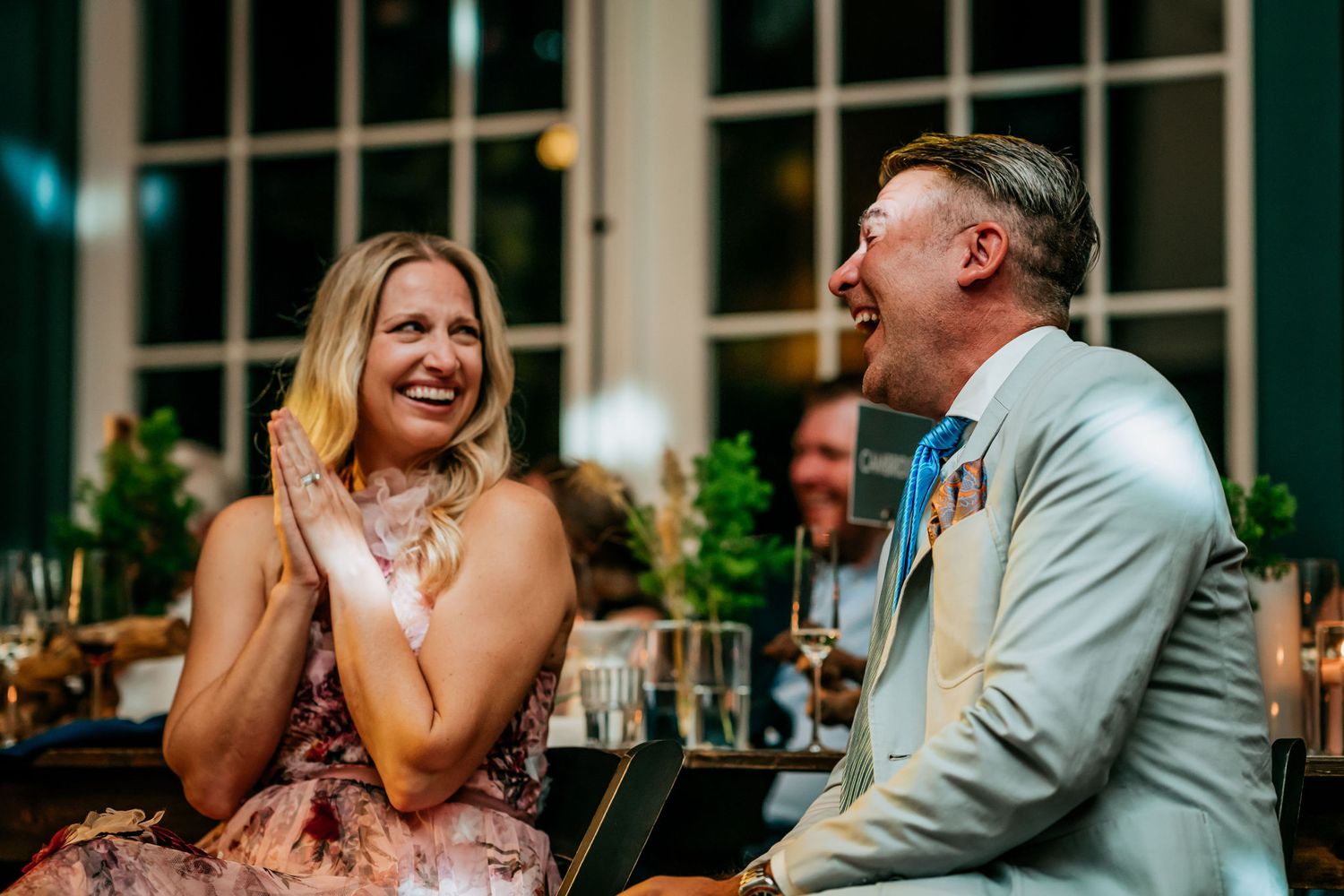 Two guests share a hearty laugh during a formal dinner event.