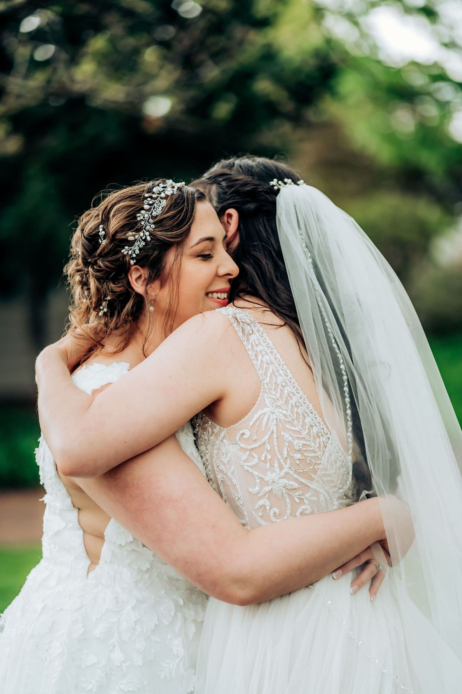 Wedding couple embraces lovingly in a romantic garden setting wearing matching white gowns.