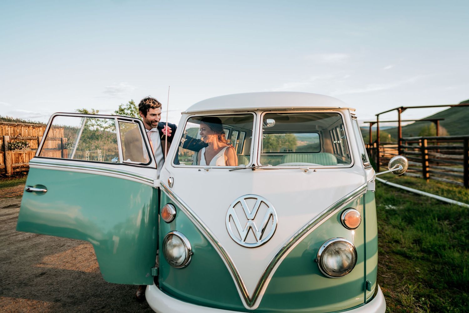 Classic turquoise and white VW bus parked in rustic outdoor setting.