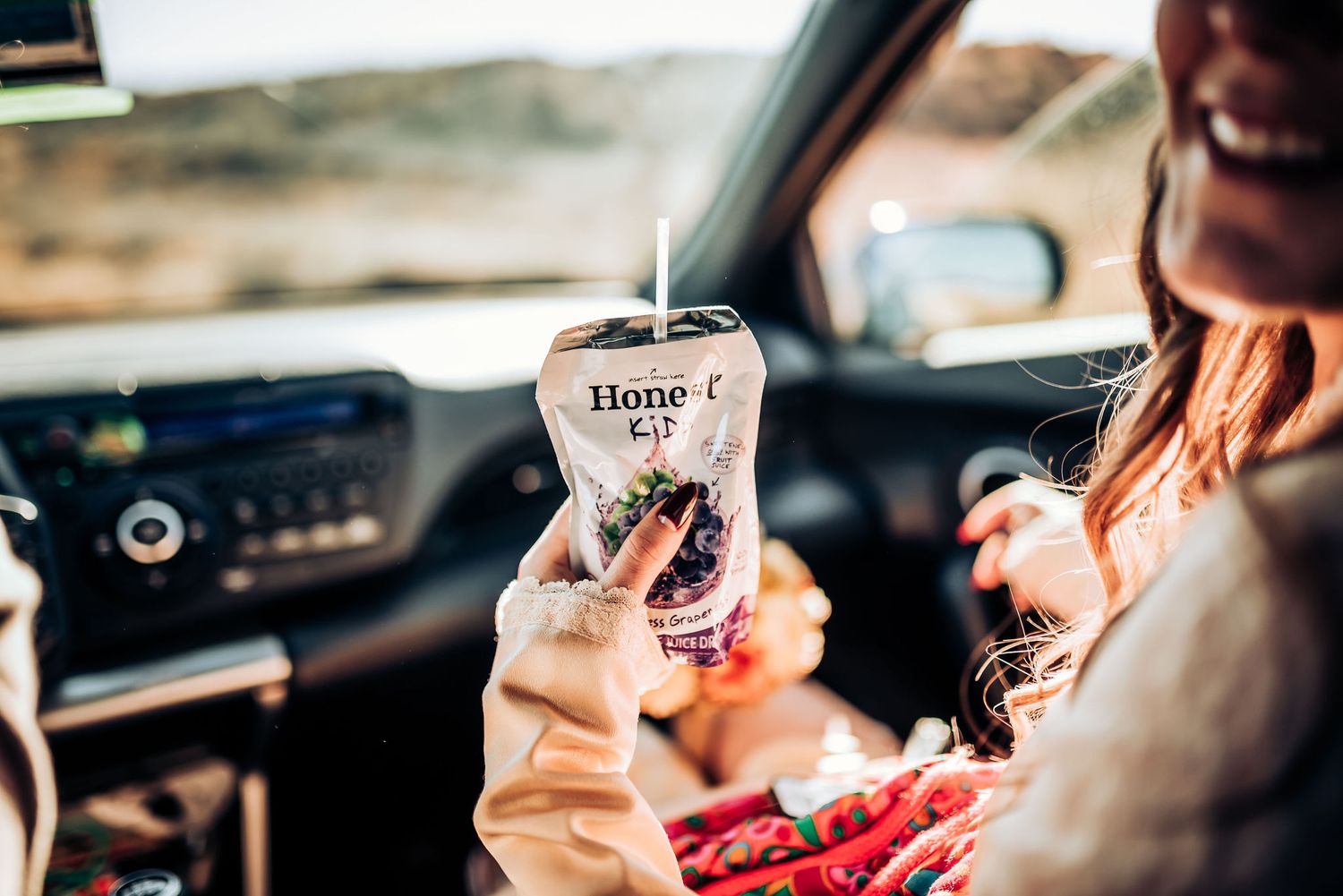 Someone holds a Home Goods coffee drink while sitting in a car during a sunny day.
