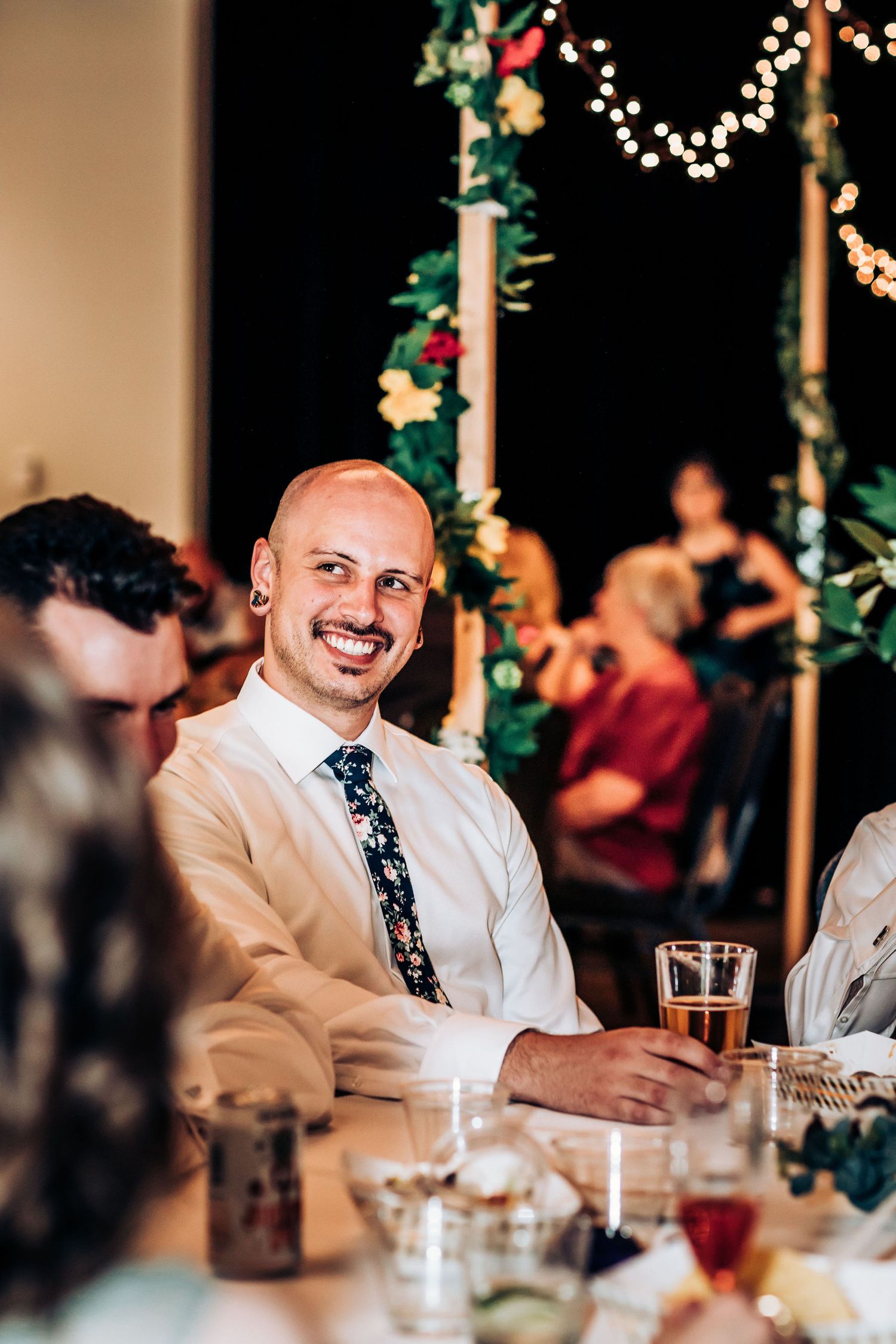 Wedding reception guest enjoying dinner and drinks under festive lighting.