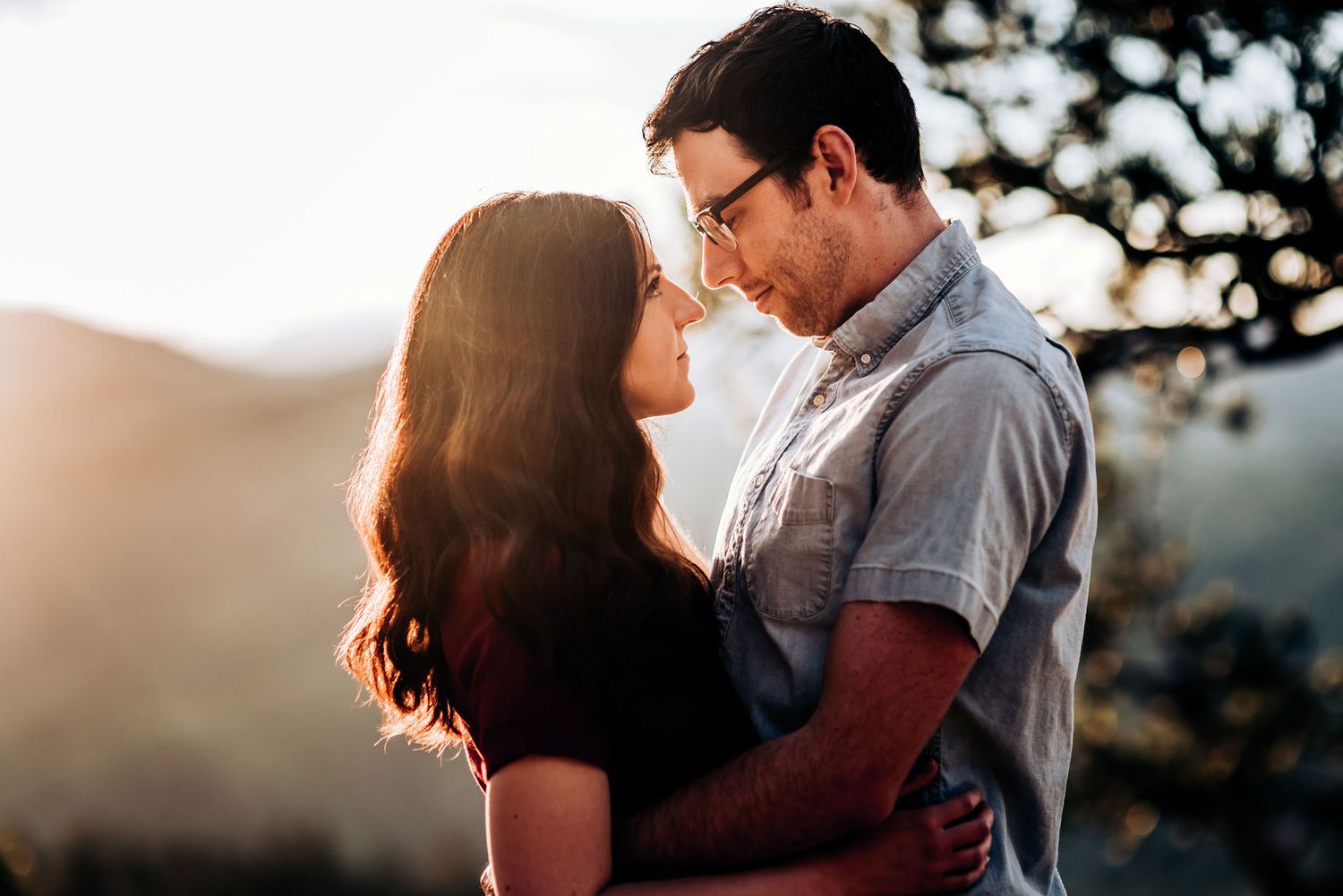 Intimate moment captured between couple during sunset in mountain setting.