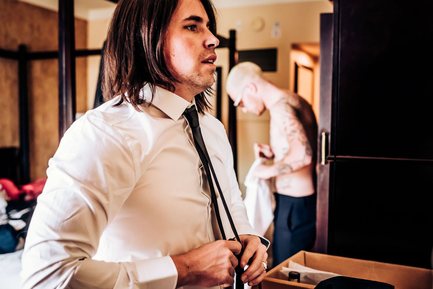 Person adjusting tie in black and white formal attire.