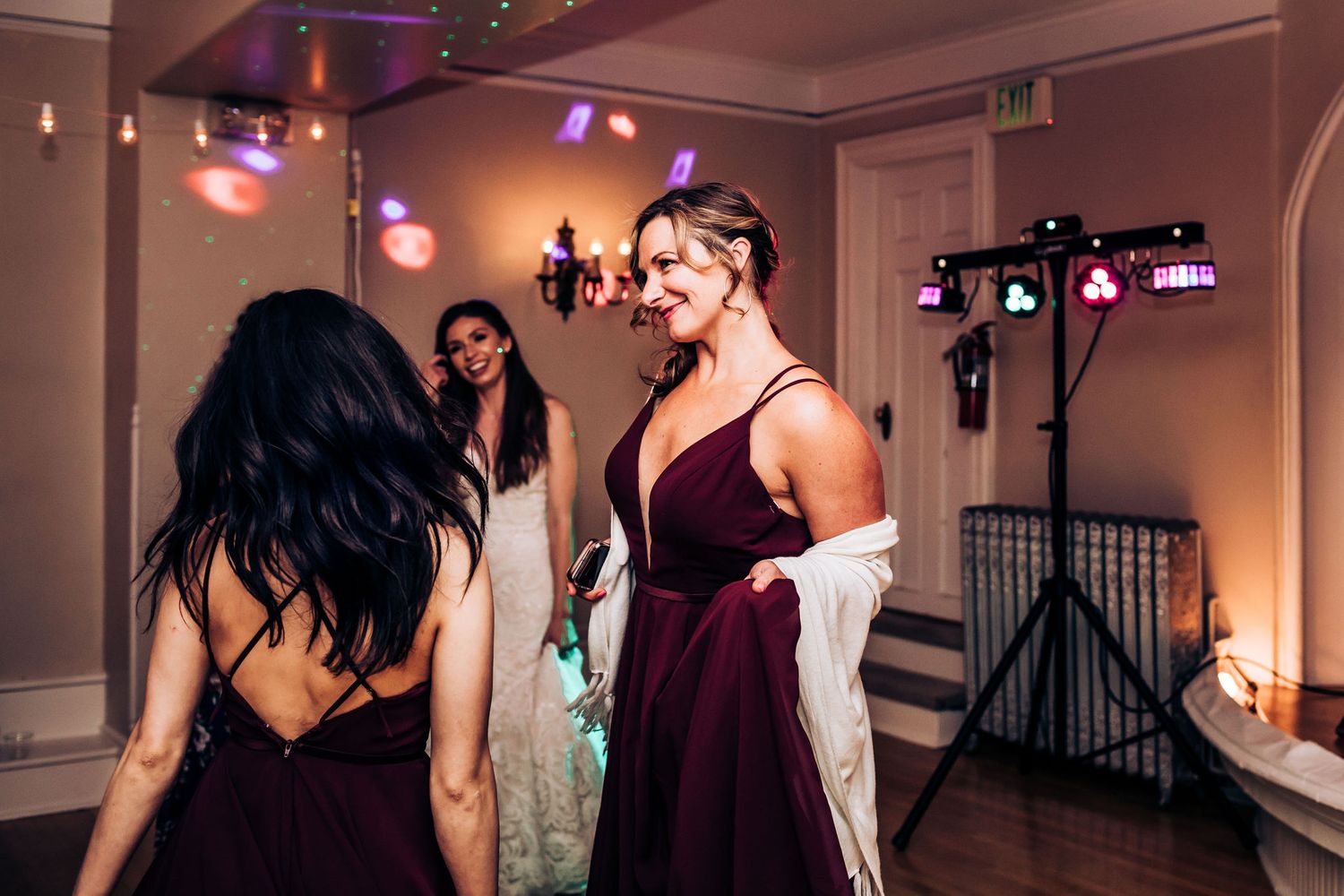 Guests in formal attire socializing at an indoor evening celebration with mood lighting.