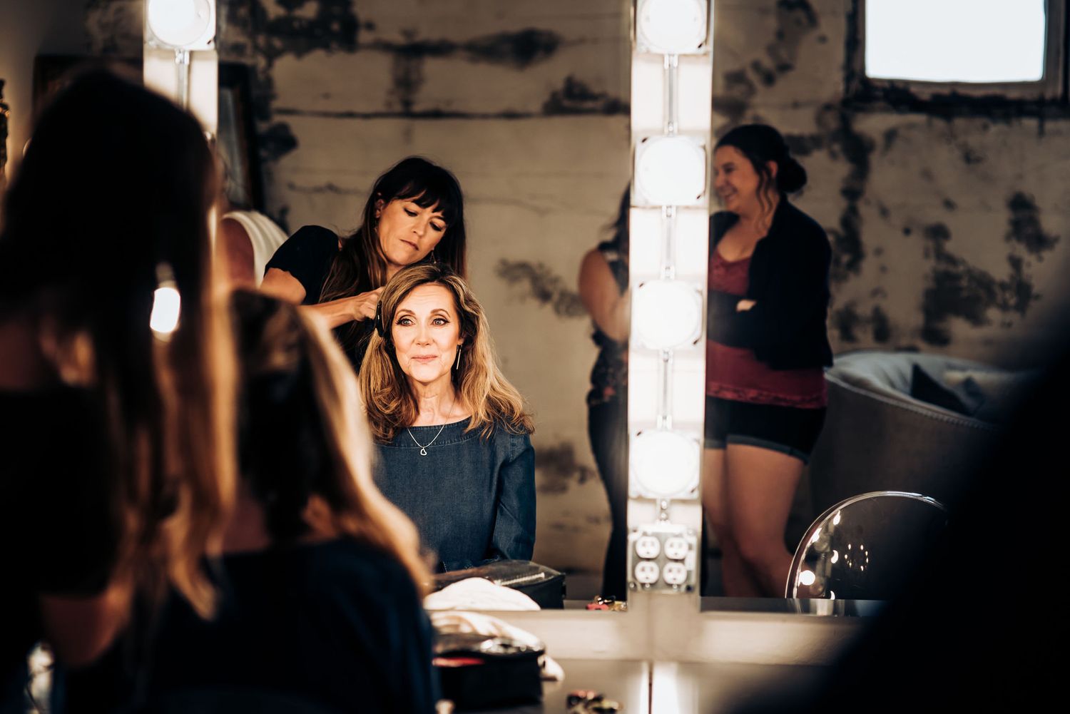 Professional beauty preparation session at a vanity mirror with studio lighting.