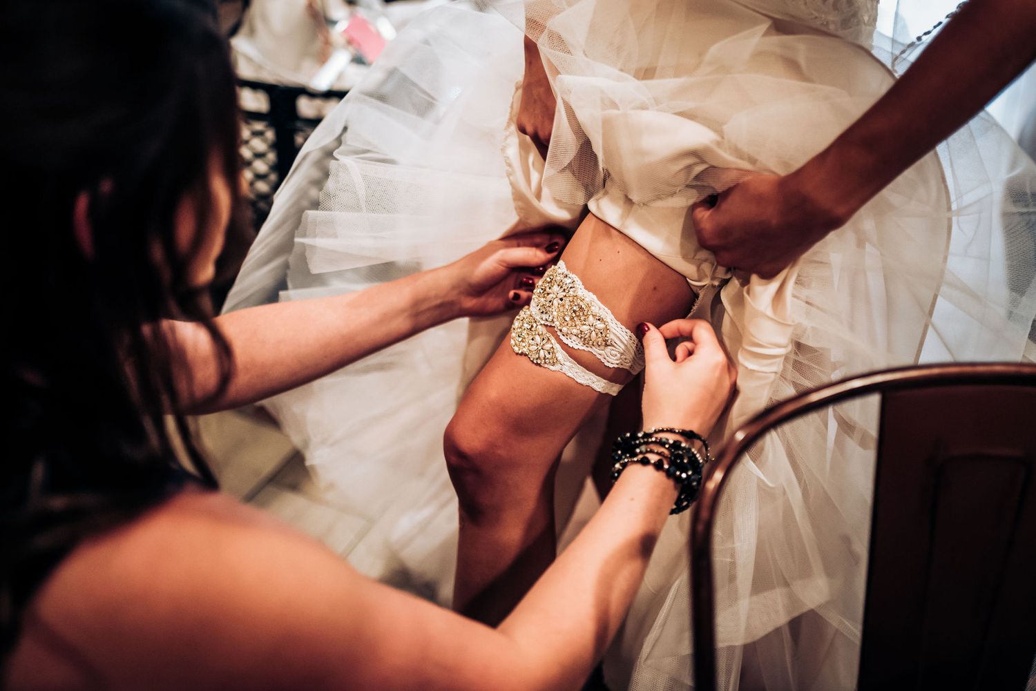 Attaching an ornate lace garter during wedding preparations.
