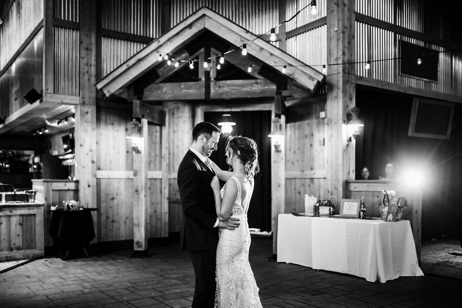 A black and white capture of a romantic dance moment in a rustic barn wedding venue.