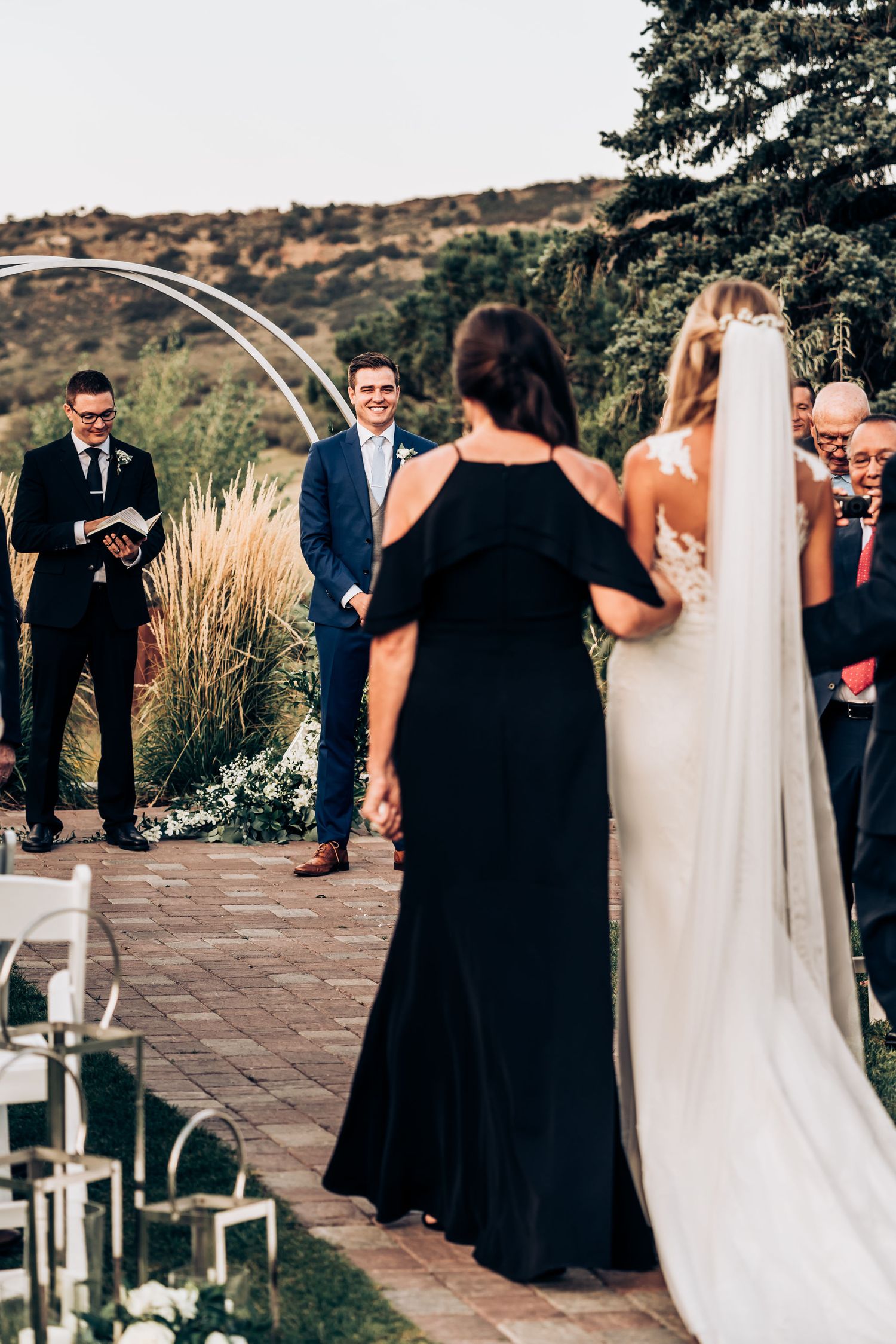 Outdoor wedding ceremony with decorated brick pathway and lanterns beneath mountain backdrop.