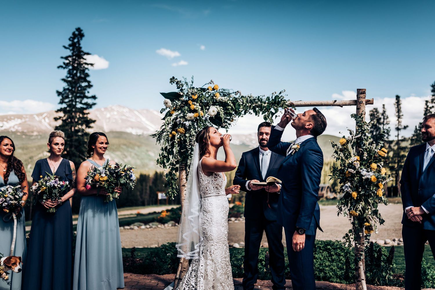 Mountain wedding ceremony under floral arch with stunning mountain backdrop.