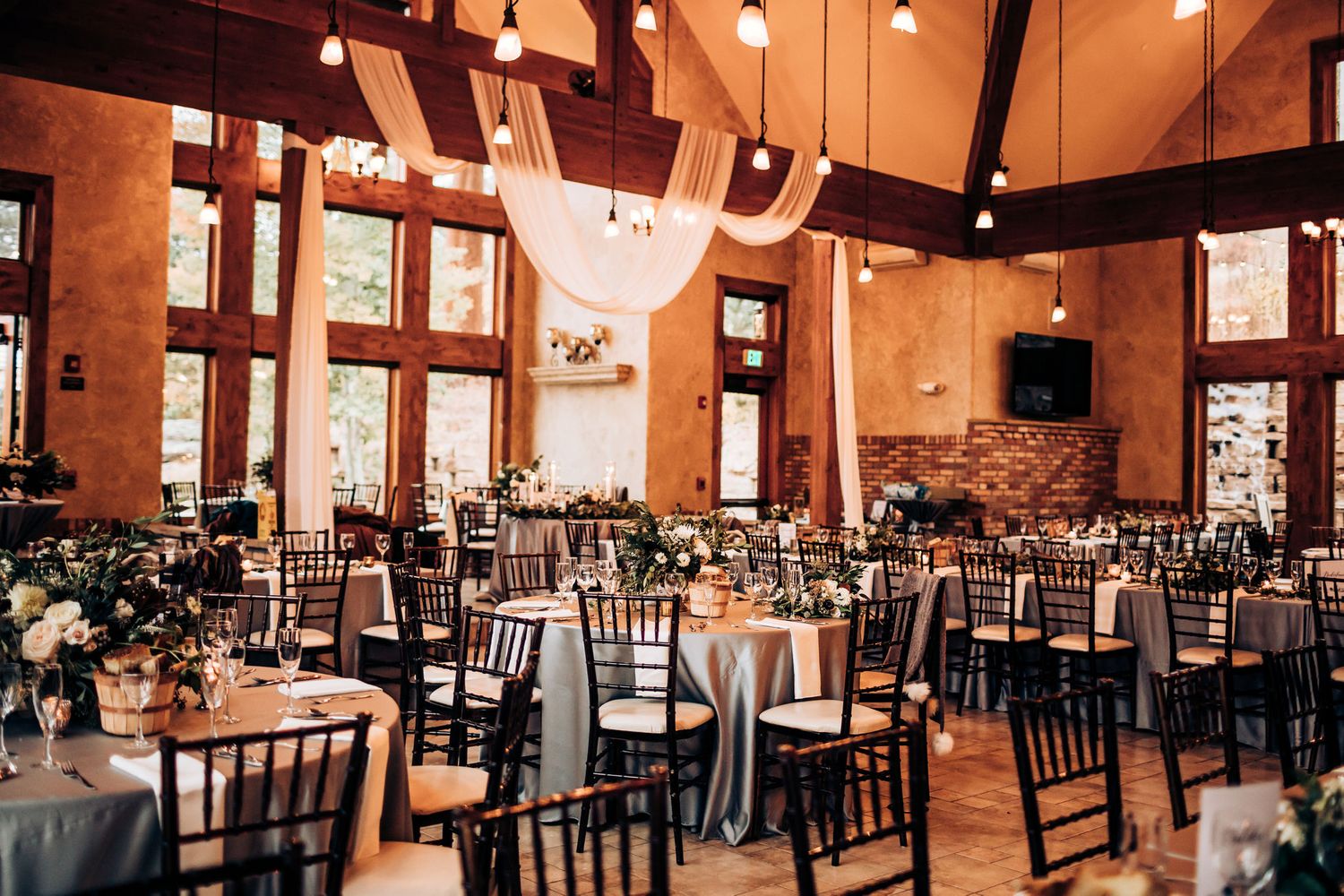 Rustic wedding reception hall with high ceilings and string lights.