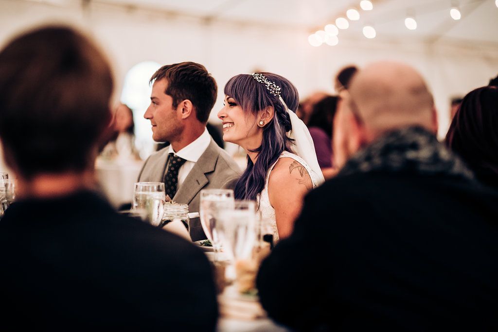 Wedding reception dinner scene with string lights and white tent overhead.
