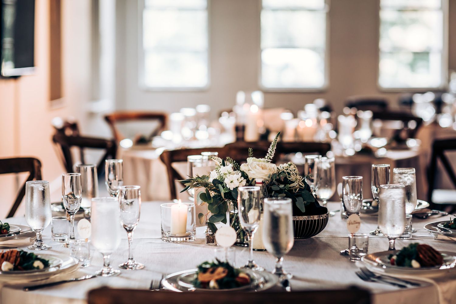 Elegant wedding reception table setting with floral centerpieces and crystal glassware.