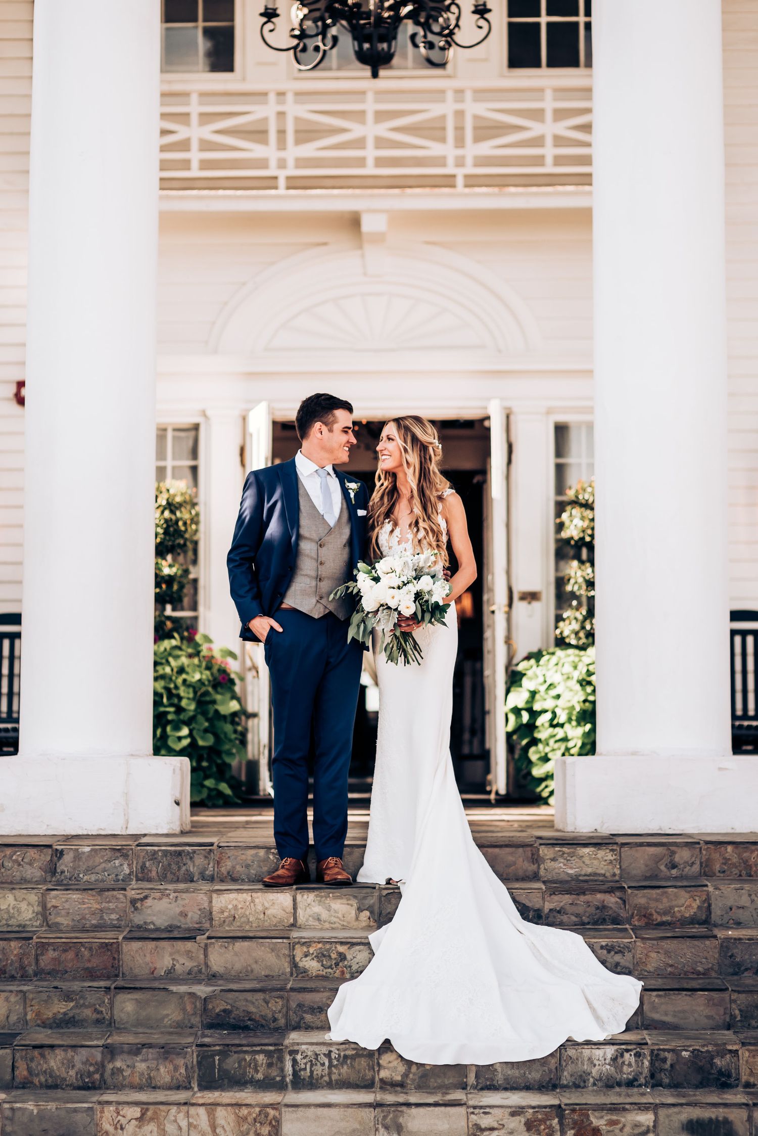 Romantic wedding portrait of couple embracing on grand entrance steps with white columns.