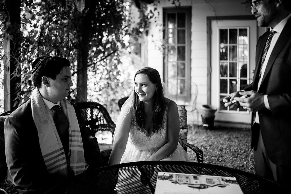 Black and white capture of joyful moment during wedding reception on porch.