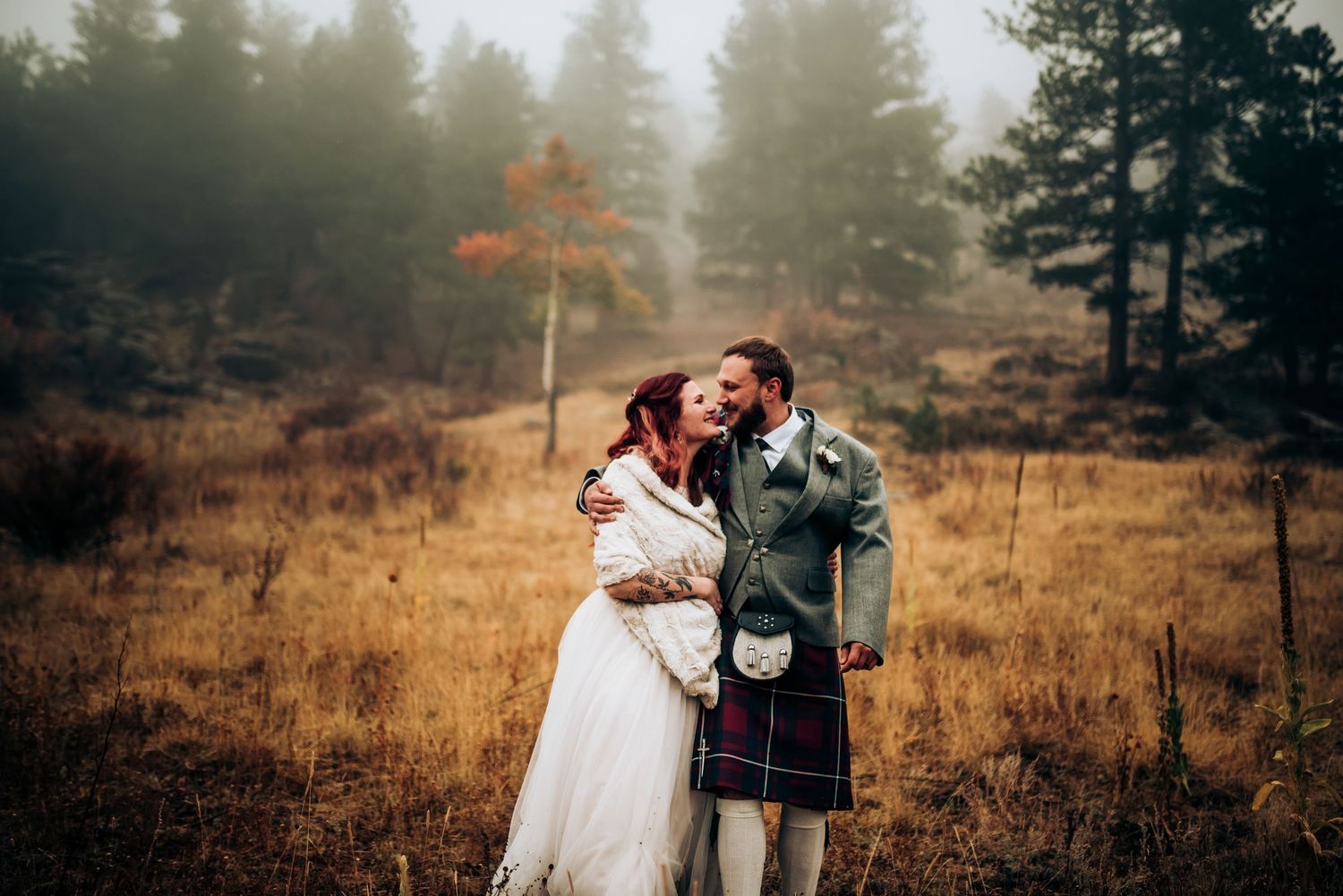 Autumn wedding scene with pine trees and golden light in mountain setting.