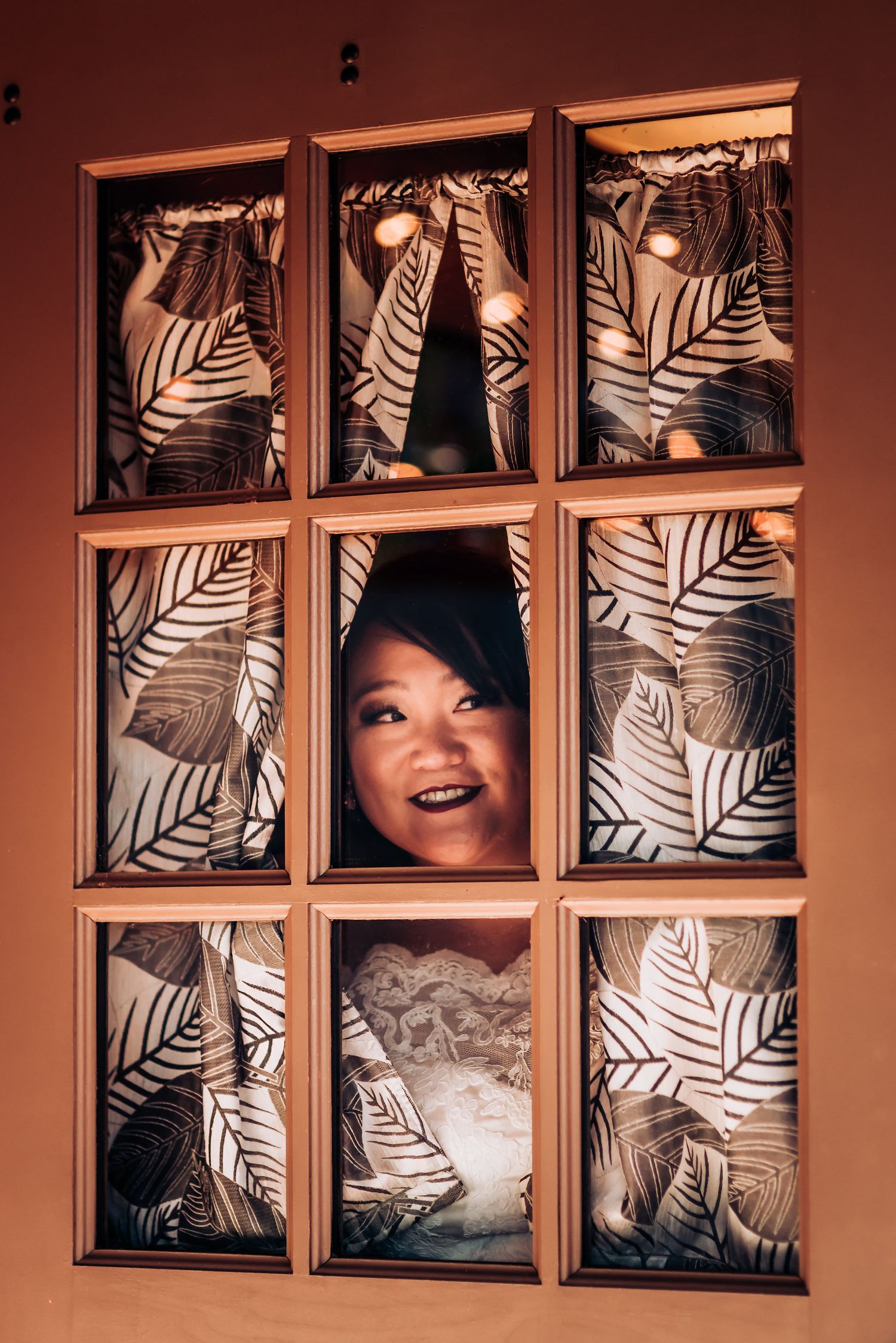 Artistic framed portrait through decorative palm leaf panels with warm lighting.