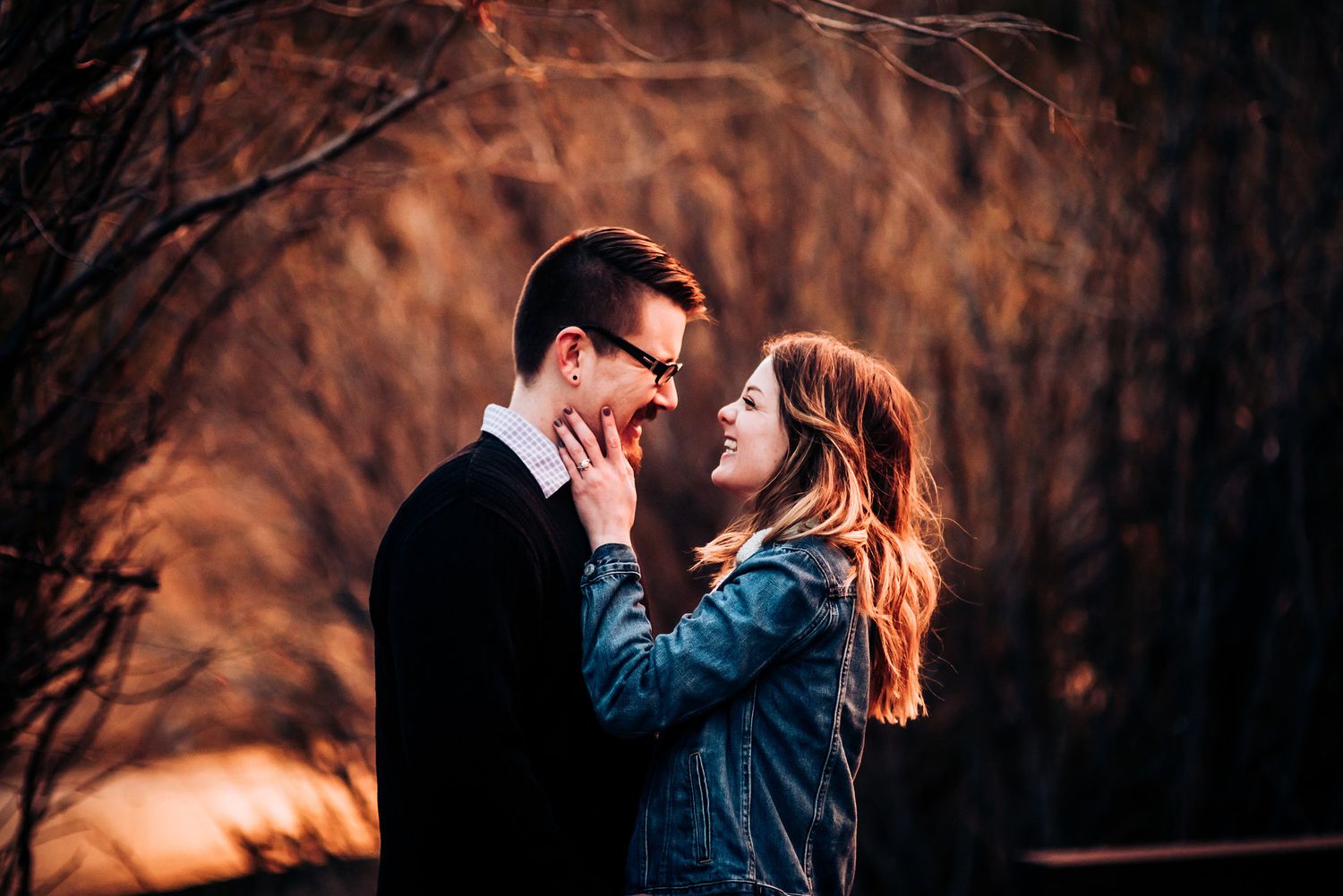 Couple embracing in romantic outdoor setting with moody autumn colors and natural lighting.