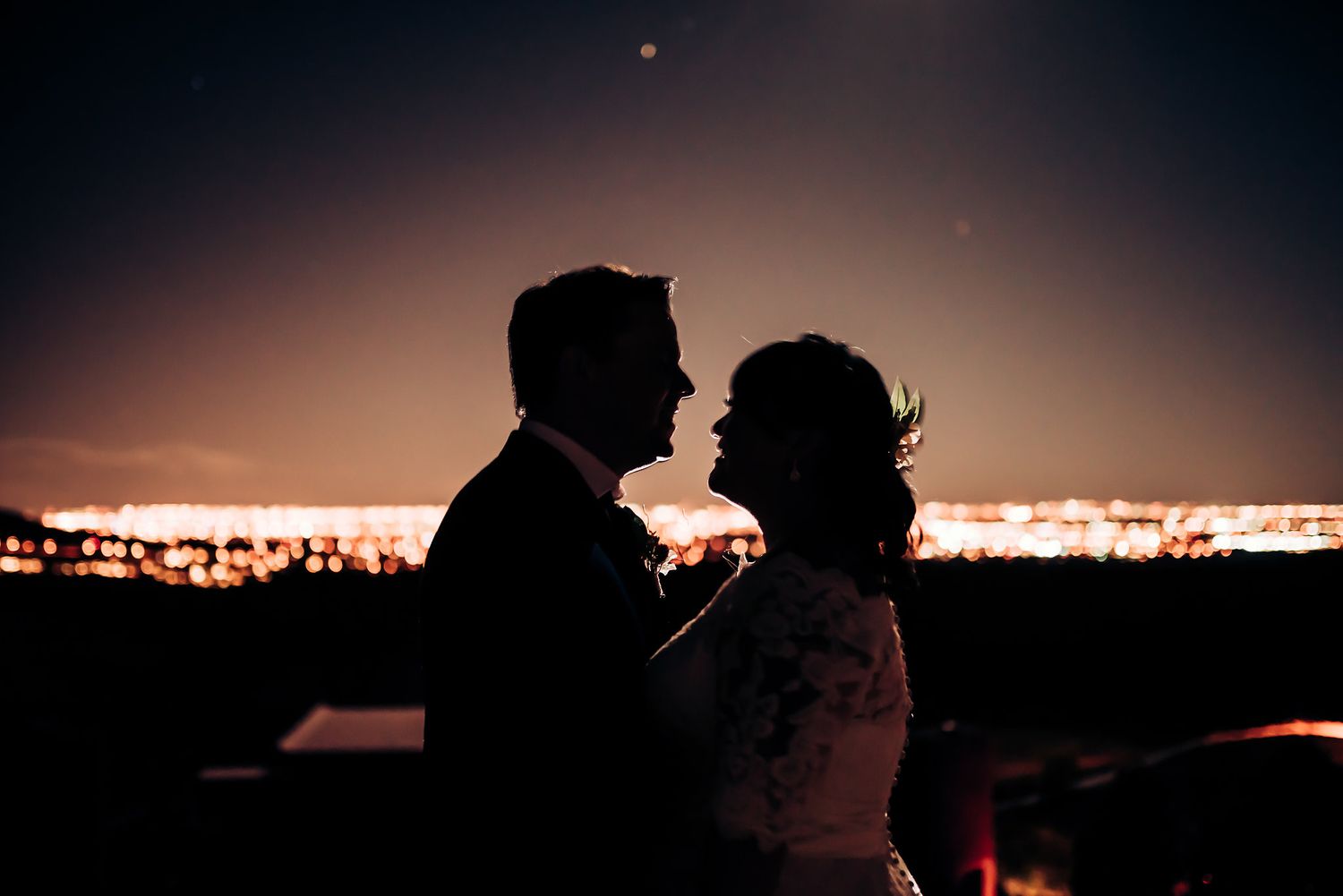 Silhouette of couple against glowing sunset cityscape in romantic moment.