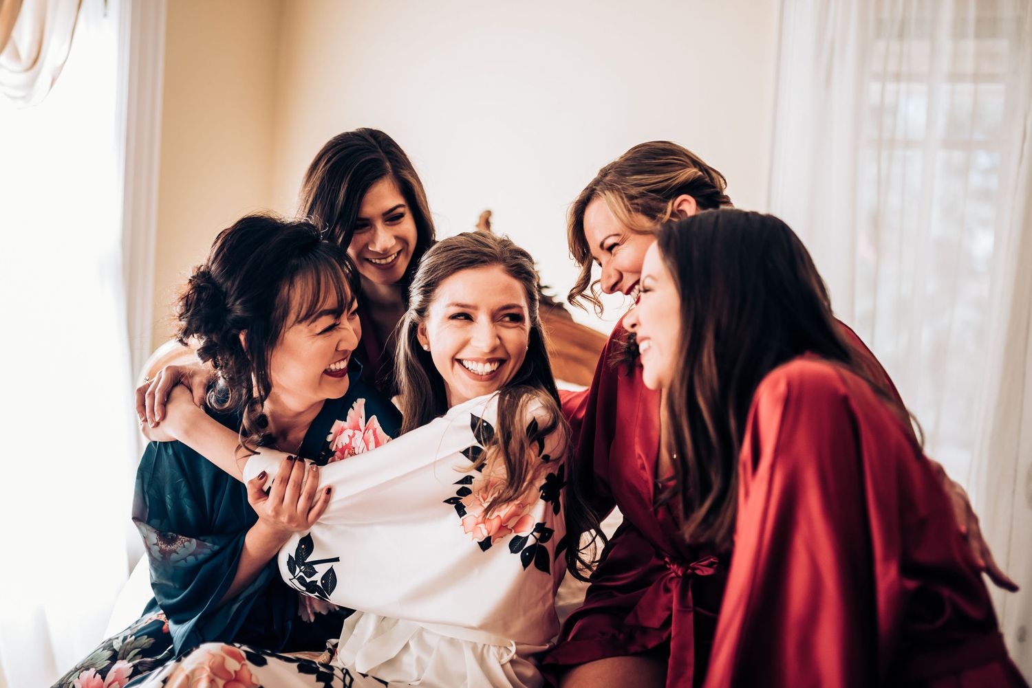 A group sharing excited laughter while gathered around during wedding preparations.