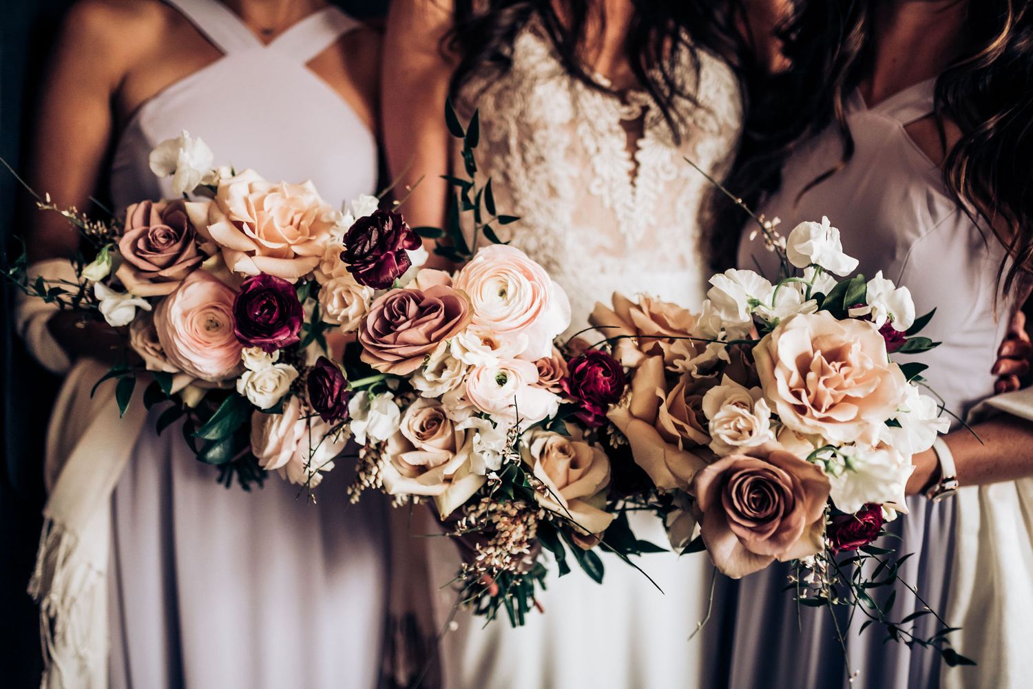 Close up of romantic blush and mauve wedding bouquets held by bridesmaids.