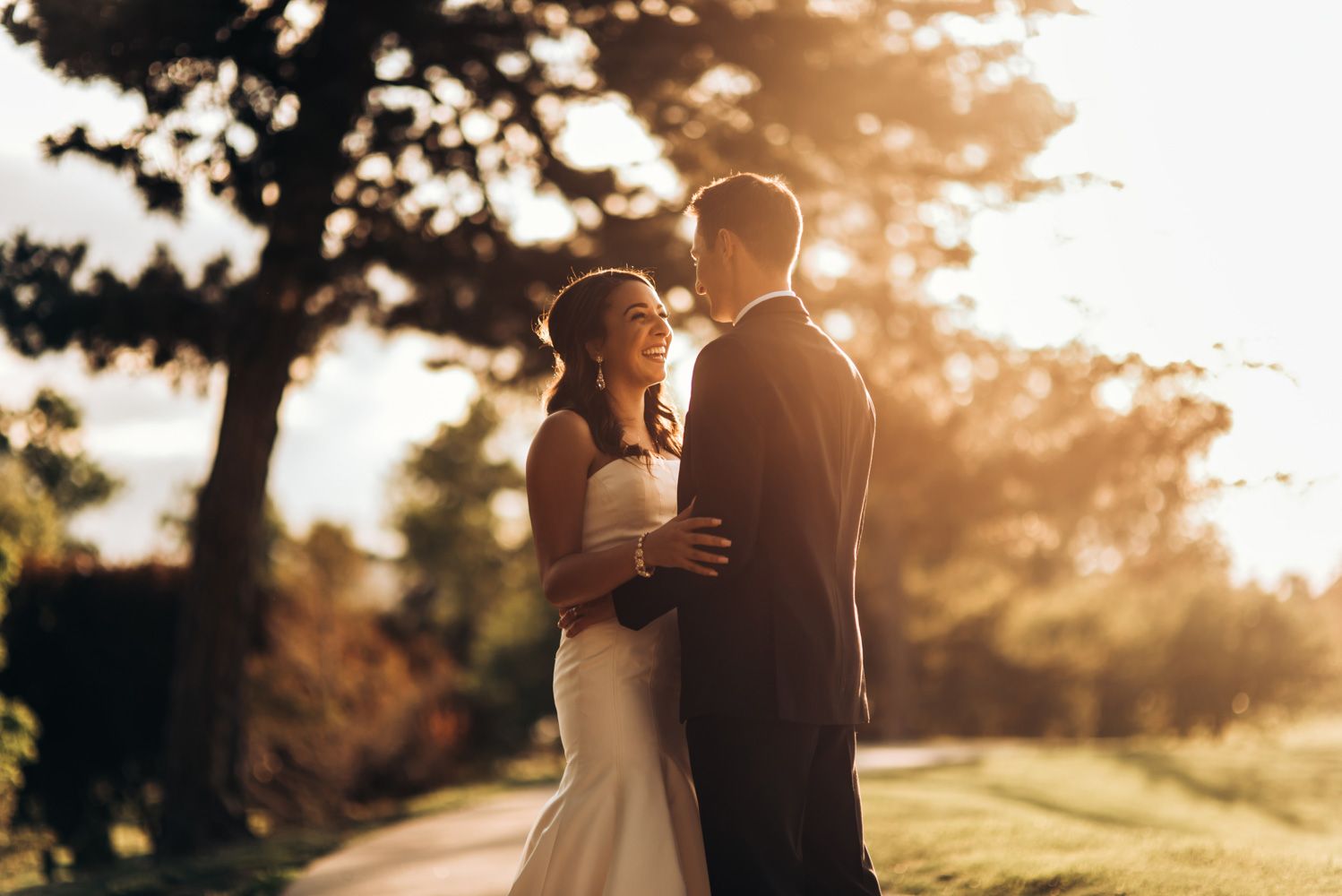 Couple in wedding attire sharing intimate moment in golden sunset light.