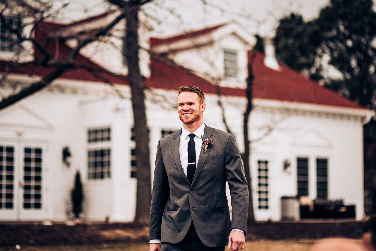 Person in white dress walks down outdoor brick pathway during wedding ceremony.