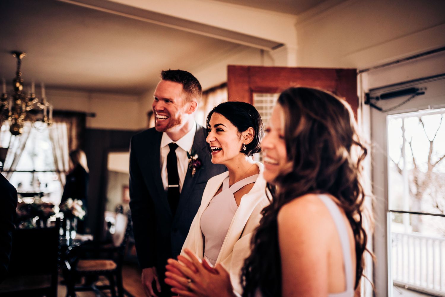 Candid celebration moment in bright interior space with chandelier.