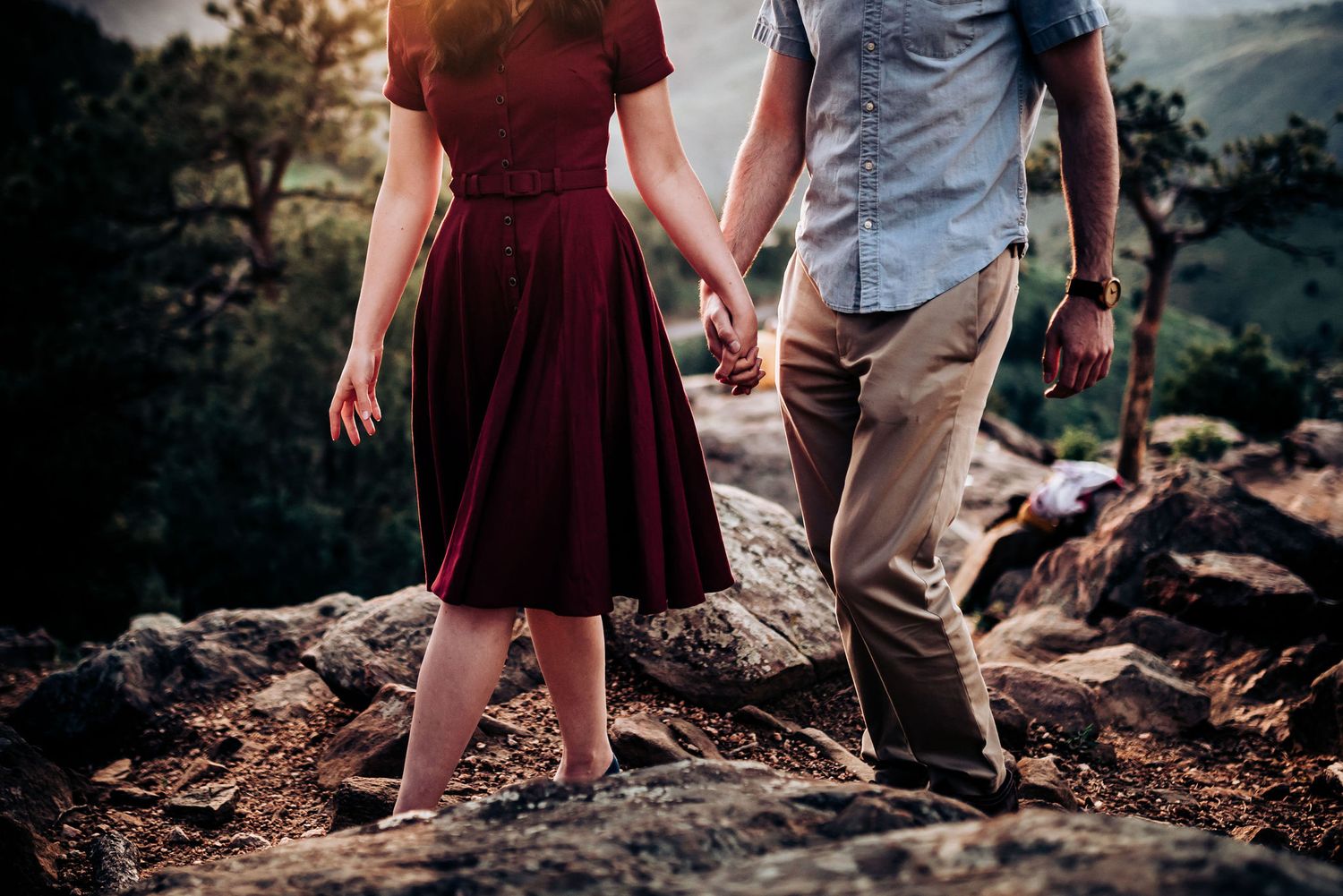 Couple walking hand in hand on rocky mountain path during outdoor adventure.