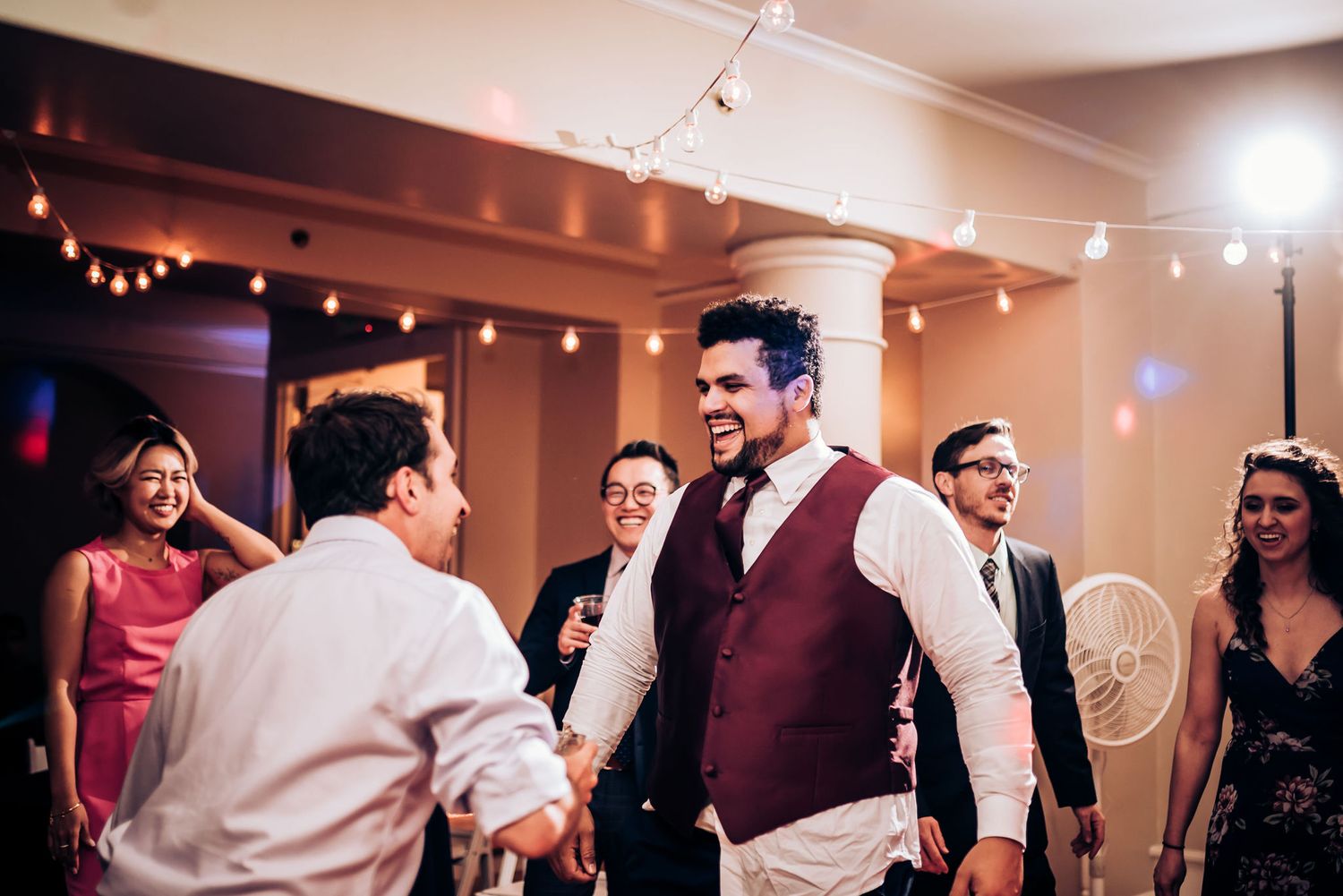 Two people share an energetic dance moment at a festive indoor celebration.