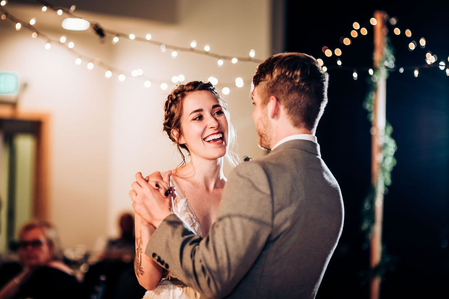 Couple shares romantic first dance under string lights at wedding reception.