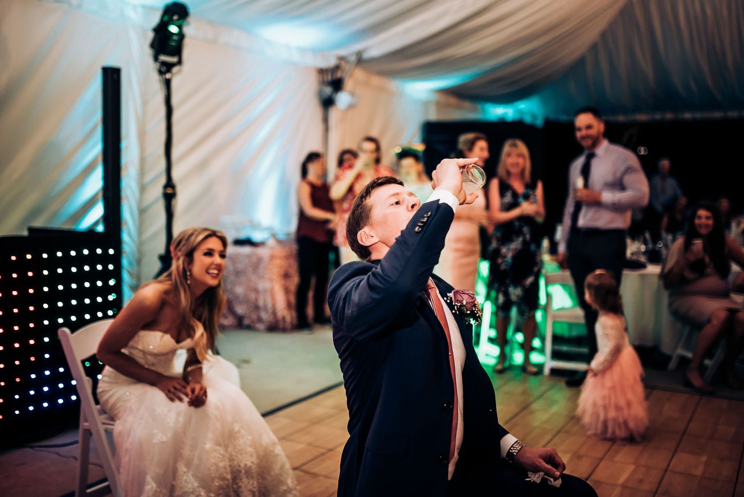 Couple sharing a dramatic dance move during their wedding reception with guests watching.
