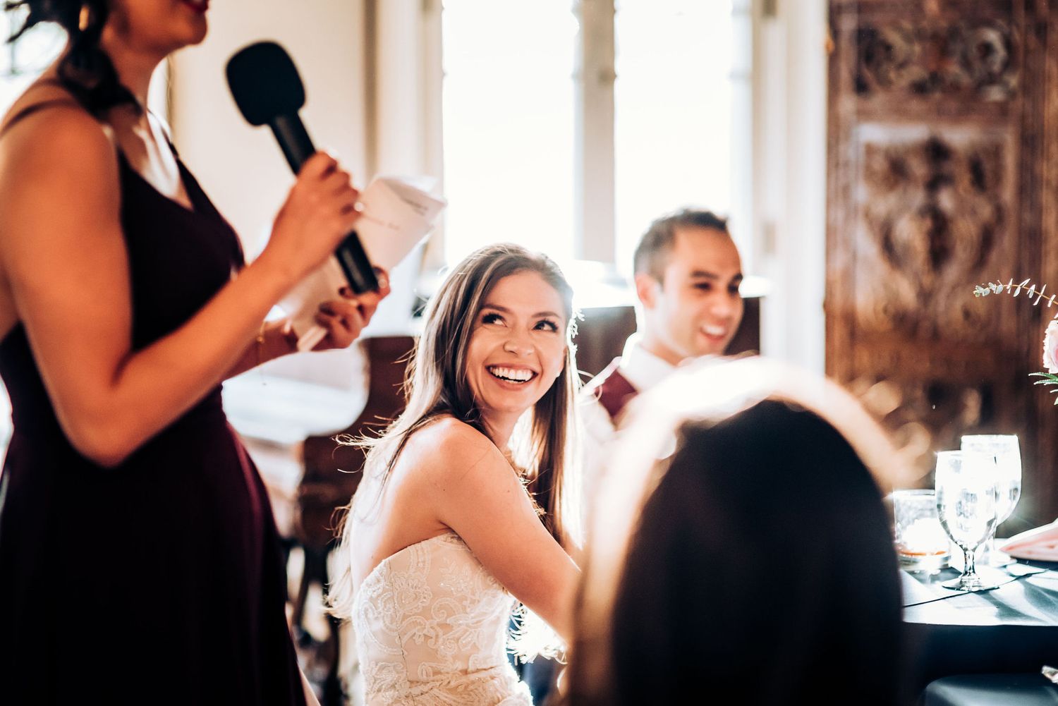 Wedding reception speech being given while guests enjoy dinner in an elegant venue.