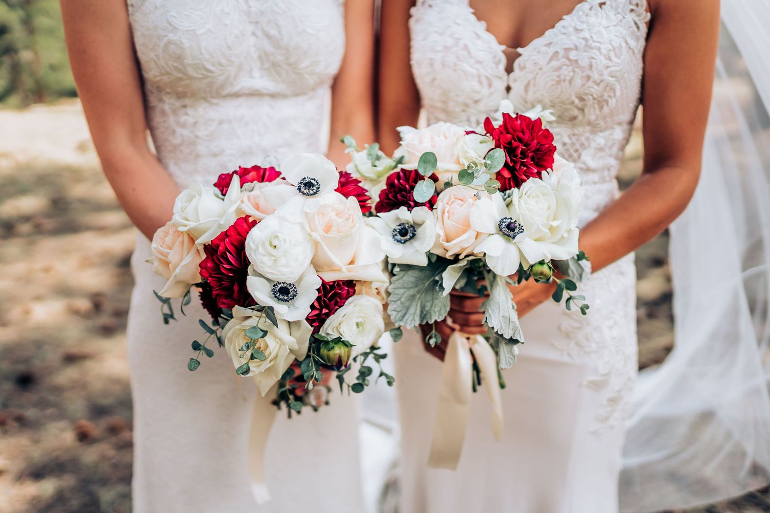 Close-up of matching white and red bridal bouquets with roses and anemones.