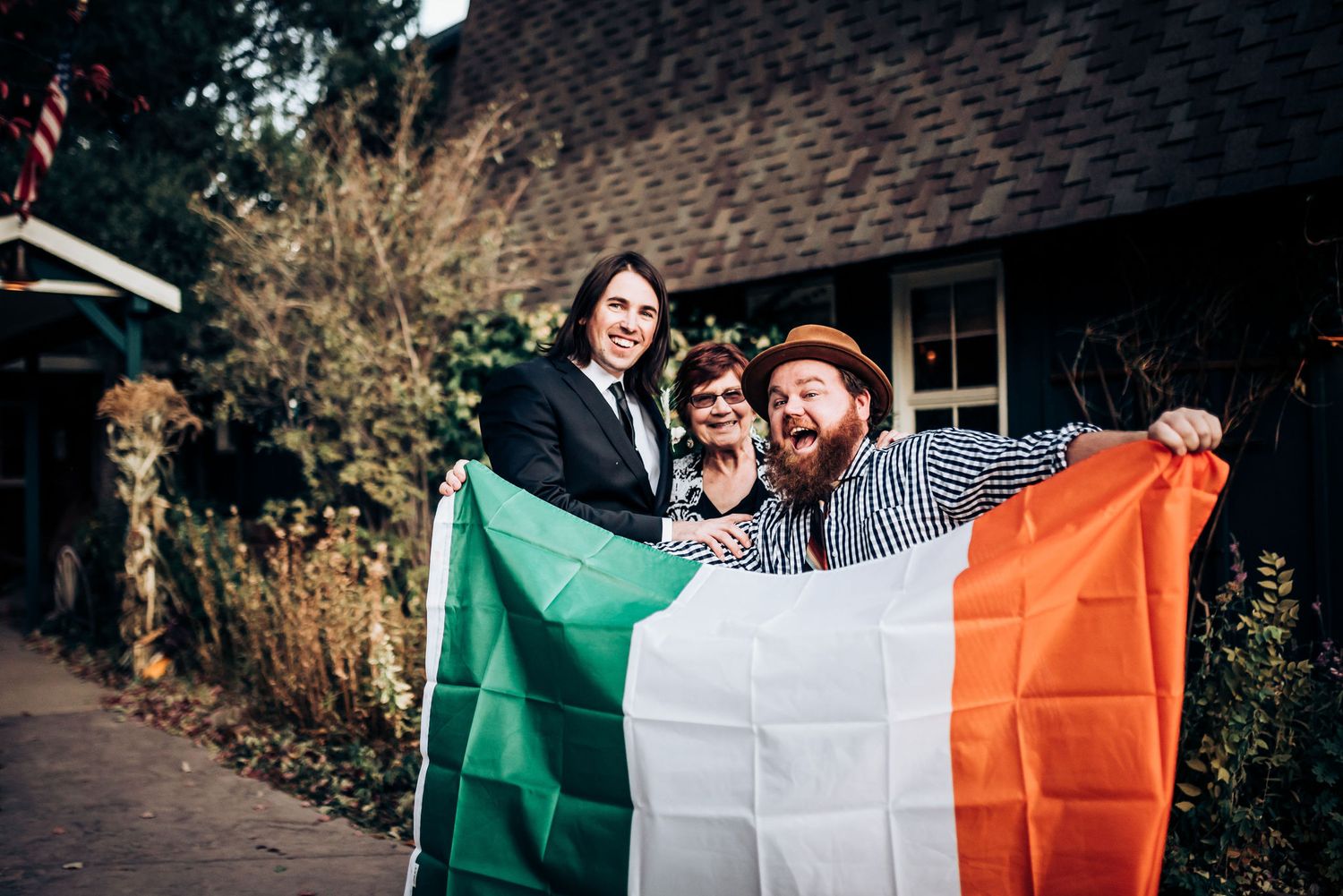 Two people holding Irish flag outdoors in front of building.